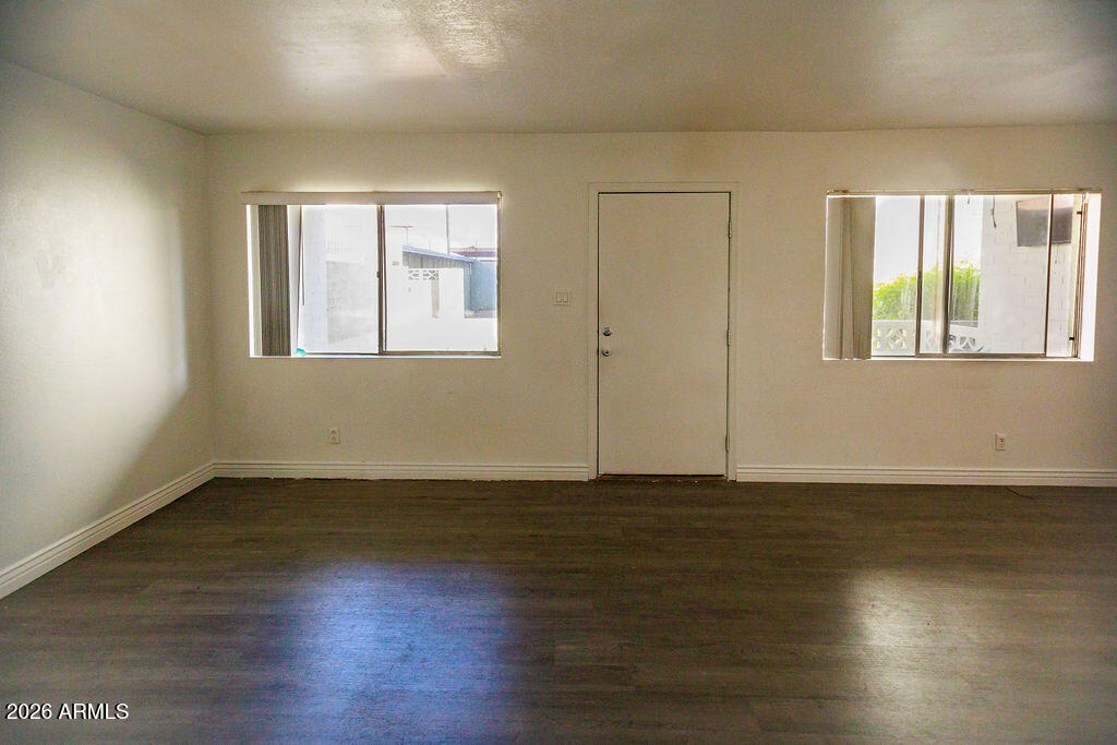 1702 West Tuckey Lane, Unit 103 Phoenix, AZ 85015 - Photo 10 of 13 a view of an empty room with wooden floor and a window