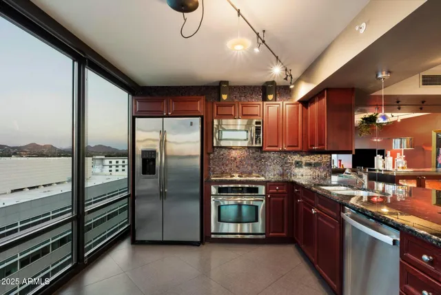 a kitchen with stainless steel appliances granite countertop a sink a stove and a refrigerator