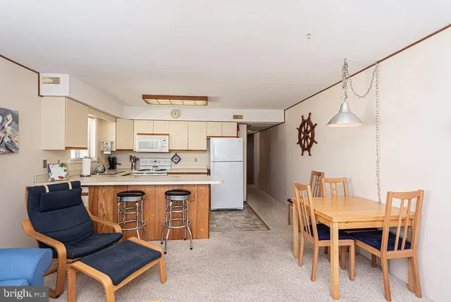 a living room with a table chairs and a refrigerator