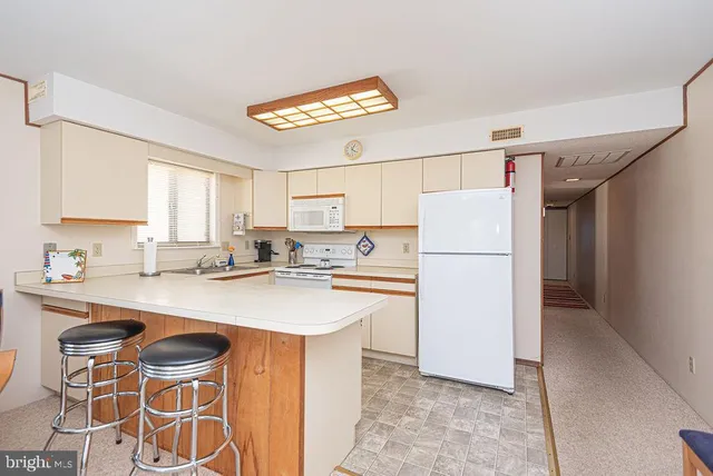 a kitchen with a sink a refrigerator and white cabinets