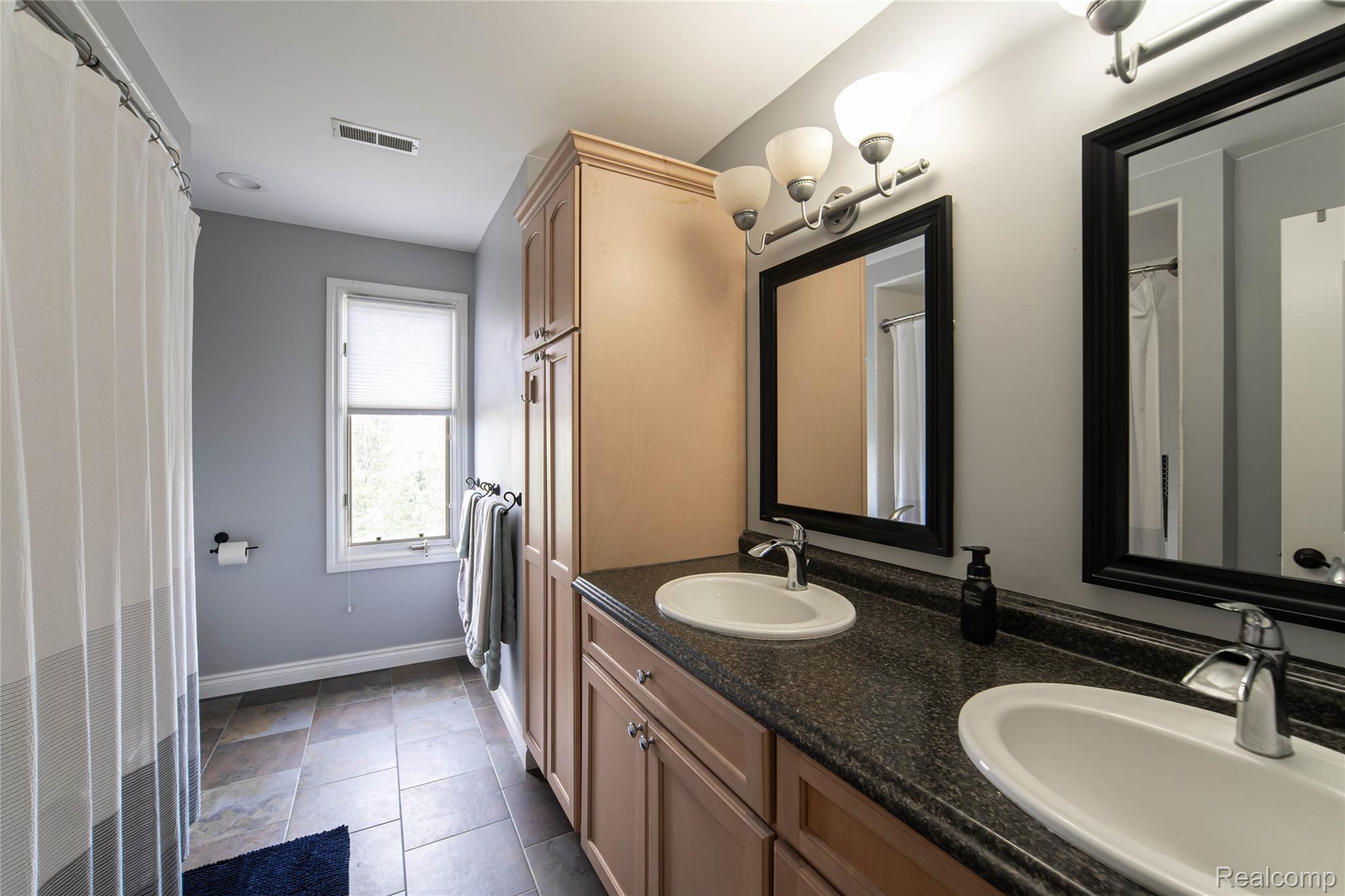 67102 Rachael Lane Washington, MI 48095 - Photo 36 of 37 Bathroom with double vanity, dark tile patterned floors, and a shower with curtain