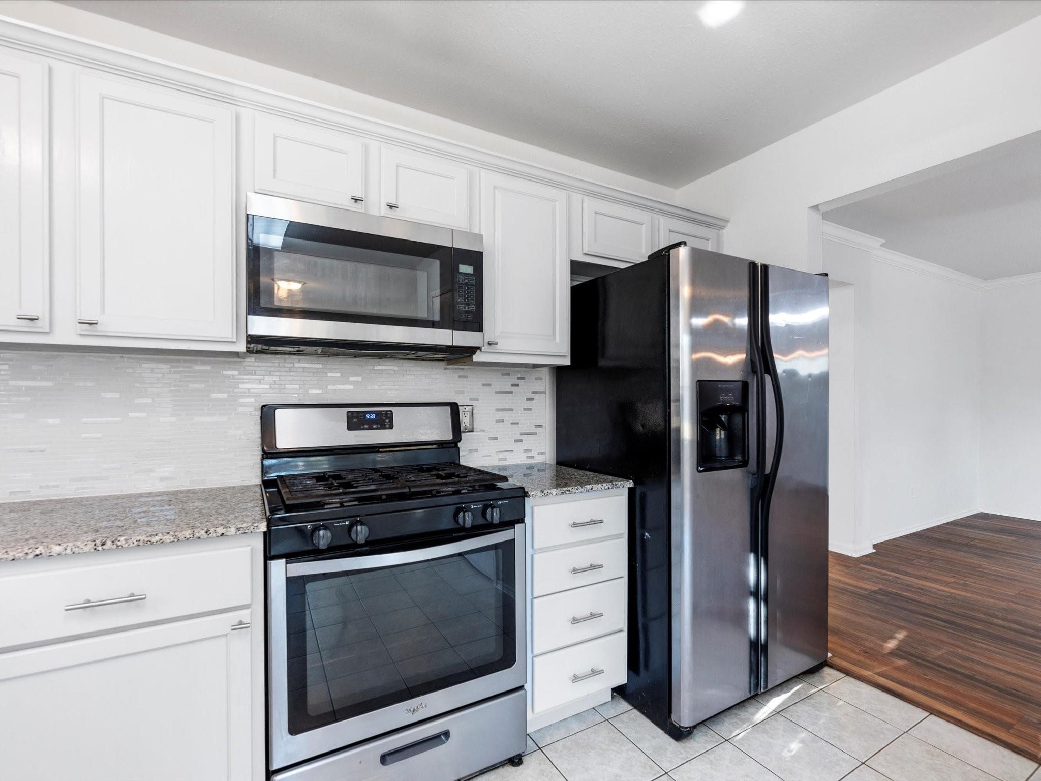 14306 Spring Marsh Court Cypress, TX 77429 - Photo 11 of 26 a kitchen with stainless steel appliances white cabinets a stove and a refrigerator