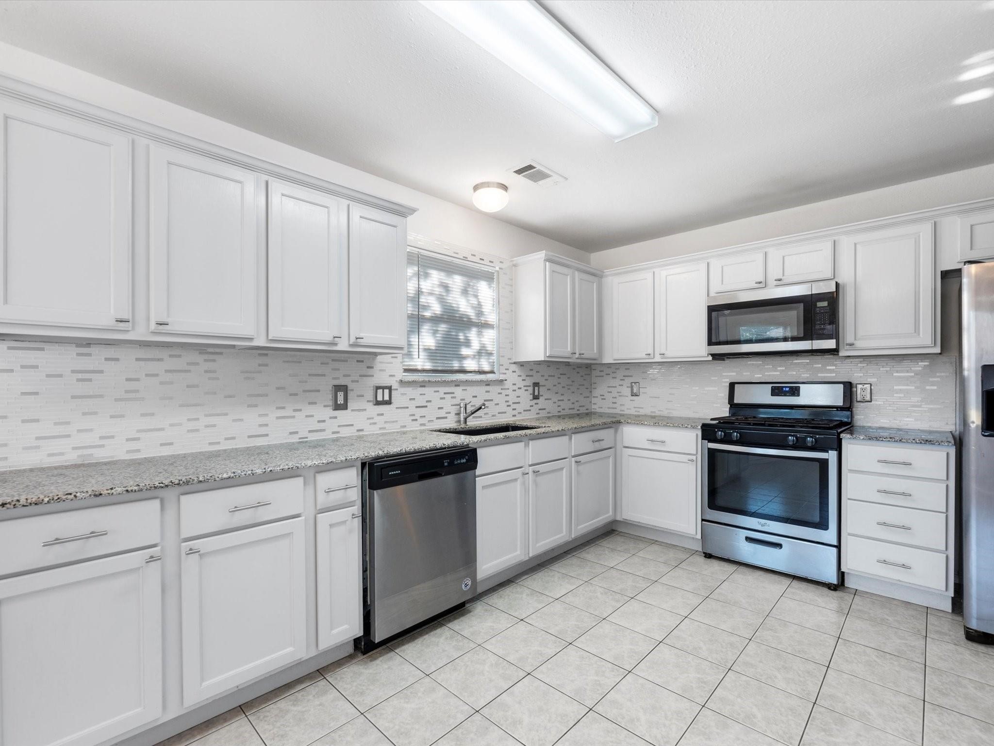 14306 Spring Marsh Court Cypress, TX 77429 - Photo 10 of 26 a kitchen with granite countertop white cabinets white stainless steel appliances with a sink and dishwasher