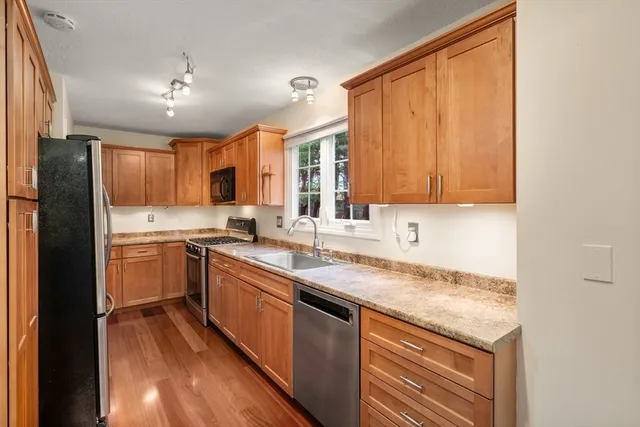 a kitchen with granite countertop stainless steel appliances a refrigerator a sink and cabinets