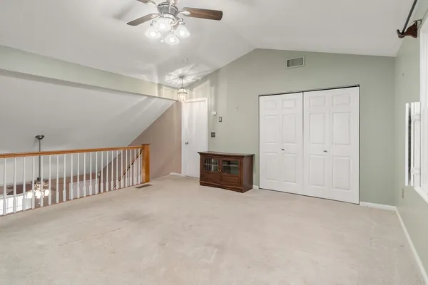 an empty room with chandelier fan and windows