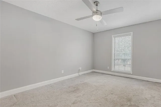 an empty room with ceiling fan and window