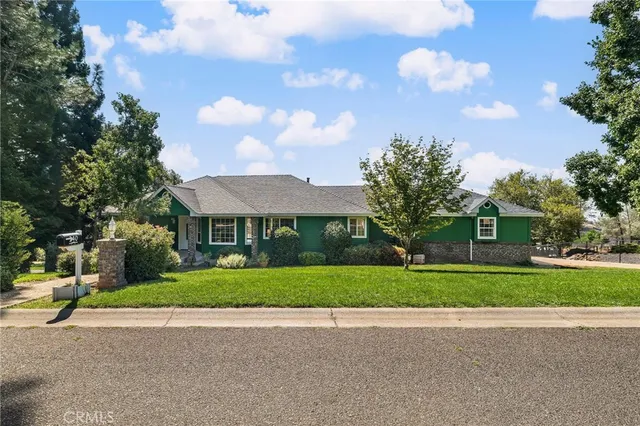 a view of a house with a yard and large trees