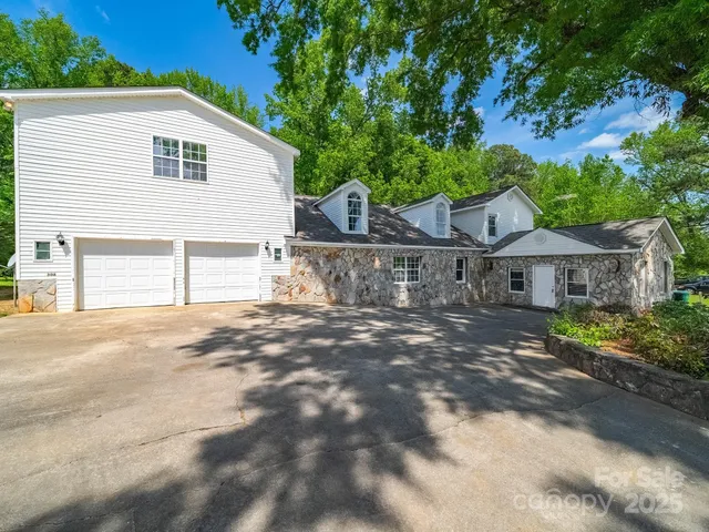 a view of a house with a yard and large tree