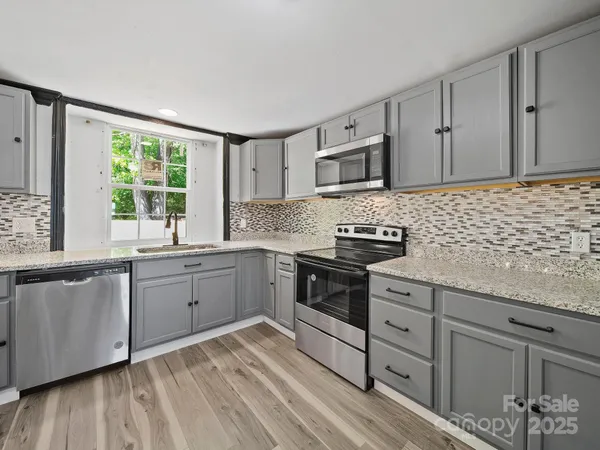 a kitchen with granite countertop cabinets stainless steel appliances a sink and a window