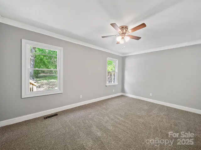 a view of an empty room with window and a fan