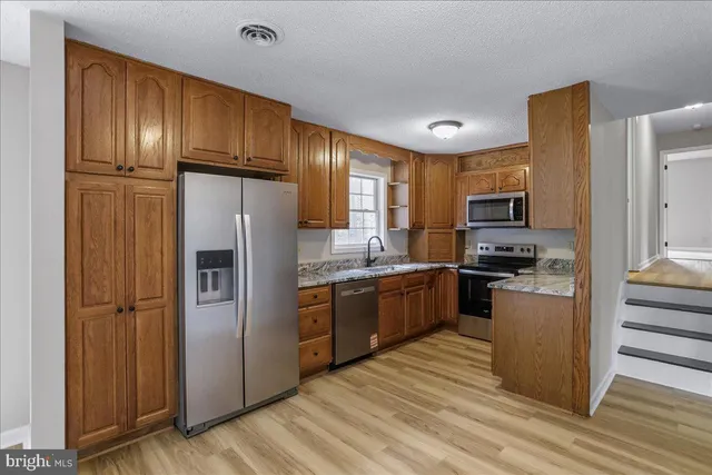 a kitchen with granite countertop stainless steel appliances and wooden cabinets