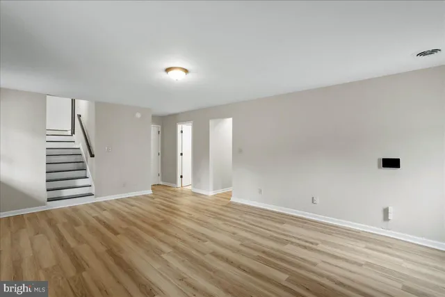 a view of an empty room with wooden floor and stairs