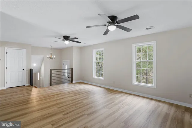 a view of empty room with wooden floor and ceiling fan
