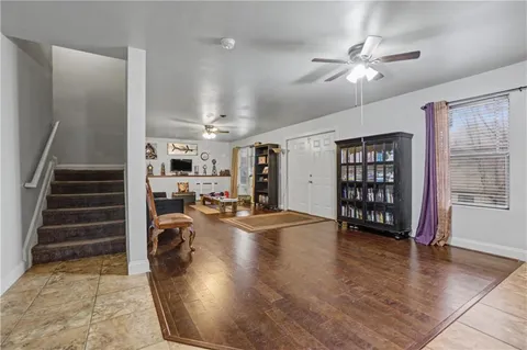 an empty room with wooden floor and way to kitchen