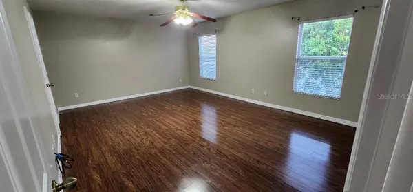 an empty room with wooden floor and windows