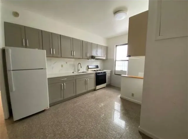 a kitchen with a sink a refrigerator and a stove top oven