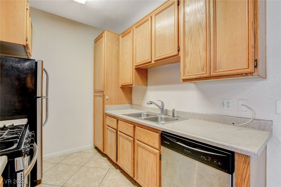 4730 East Craig Road, Unit 1005 Las Vegas, NV 89115 - Photo 16 of 45 Kitchen with appliances with stainless steel finishes, light brown cabinetry, light countertops, and light tile patterned flooring