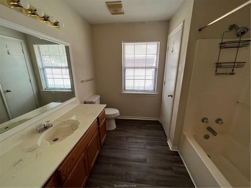 4611 Brompton Lane Bryan, TX 77802 - Photo 12 of 18 Bathroom featuring vanity, shower combination, and dark wood-type flooring