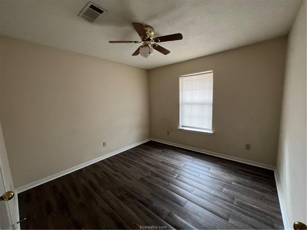 4611 Brompton Lane Bryan, TX 77802 - Photo 13 of 18 Empty room with dark wood-style flooring, a ceiling fan, and a textured ceiling