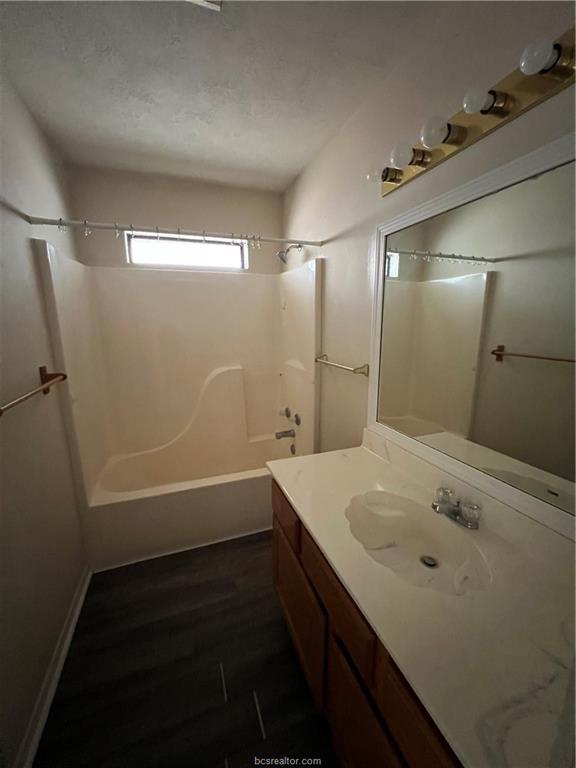 4611 Brompton Lane Bryan, TX 77802 - Photo 15 of 18 Bathroom featuring vanity, shower combination, and dark wood-style flooring
