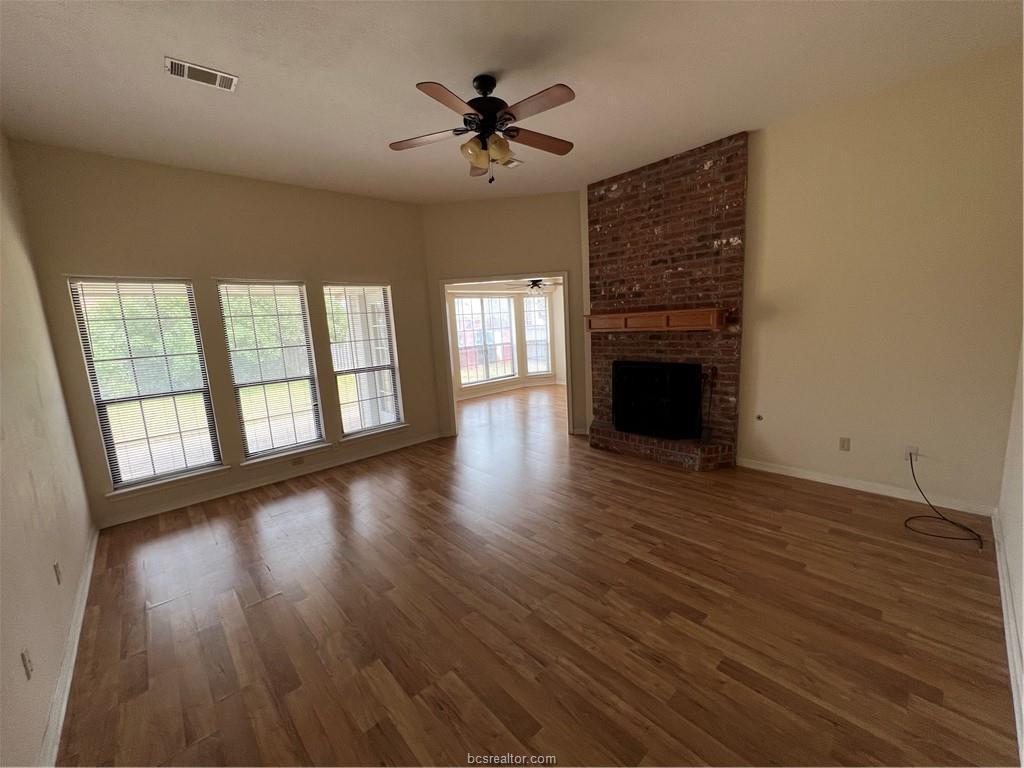 4611 Brompton Lane Bryan, TX 77802 - Photo 3 of 18 Unfurnished living room featuring a ceiling fan, dark wood-type flooring, and a brick fireplace