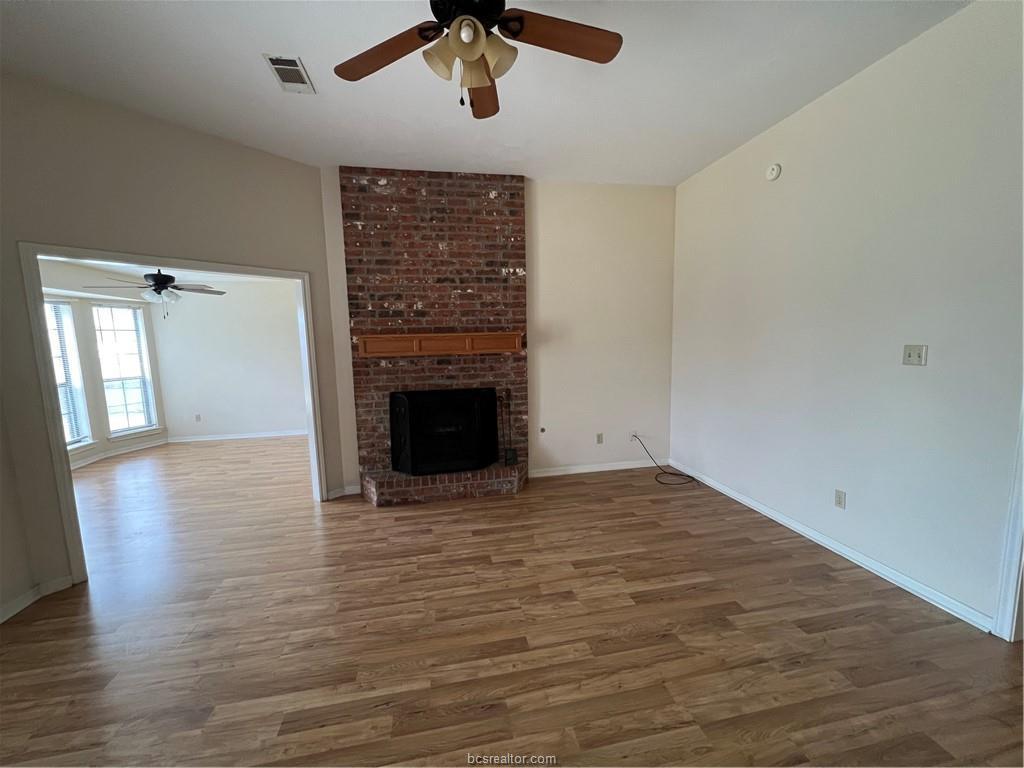 4611 Brompton Lane Bryan, TX 77802 - Photo 4 of 18 Unfurnished living room with ceiling fan, wood finished floors, and a fireplace