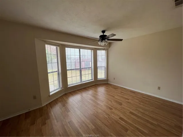 a view of an empty room with a window and wooden floor