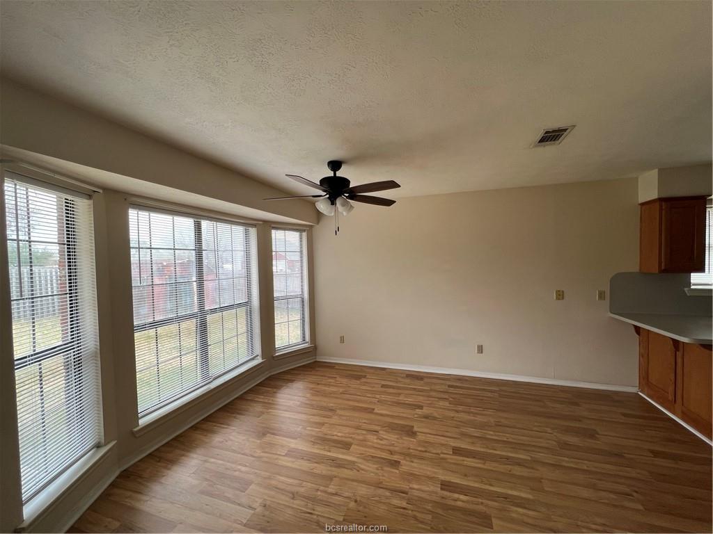 4611 Brompton Lane Bryan, TX 77802 - Photo 7 of 18 Unfurnished dining area featuring light wood-style flooring, a textured ceiling, and a ceiling fan