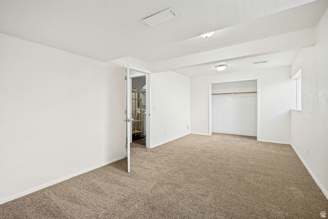 5529 Ridge Hollow Way Kearns, UT 84118 - Photo 18 of 23 Carpeted room featuring white walls, a visible closet with hanging rod, and a window