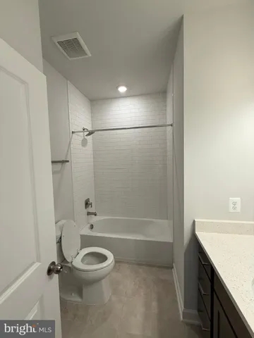 a bathroom with a granite countertop sink toilet a mirror and shower
