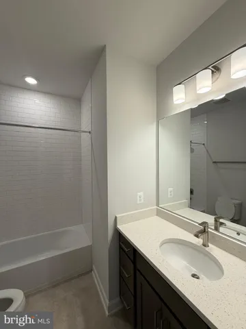 a bathroom with a granite countertop sink a toilet and shower