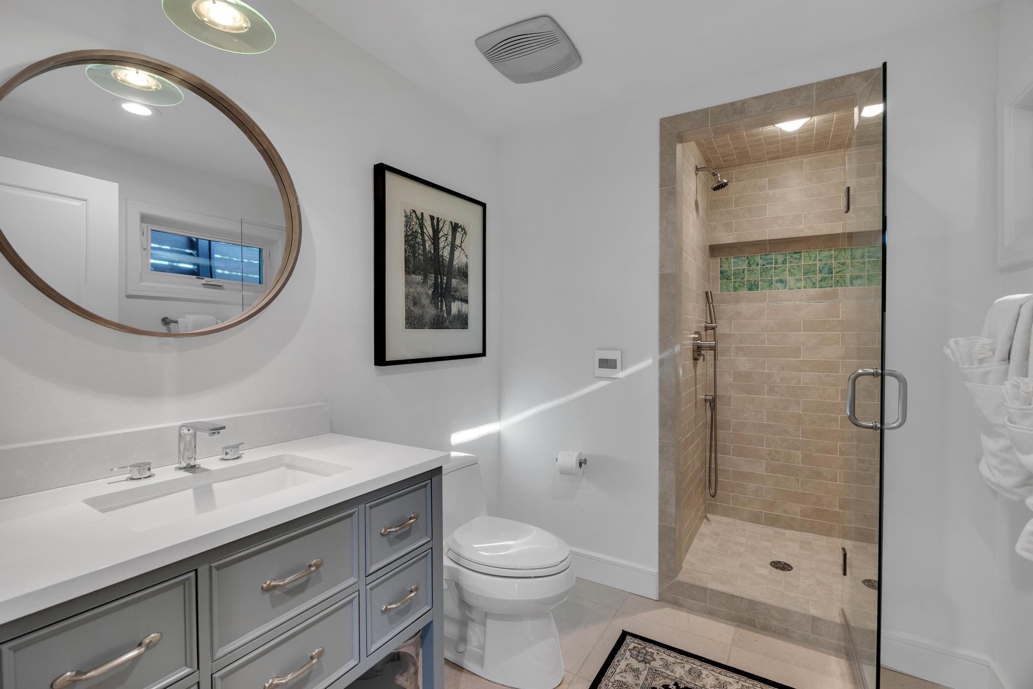 24710 Fossil Trail Spicewood, TX 78669 - Photo 13 of 40 a bathroom with a toilet a sink a glass door a shower a mirror and vanity