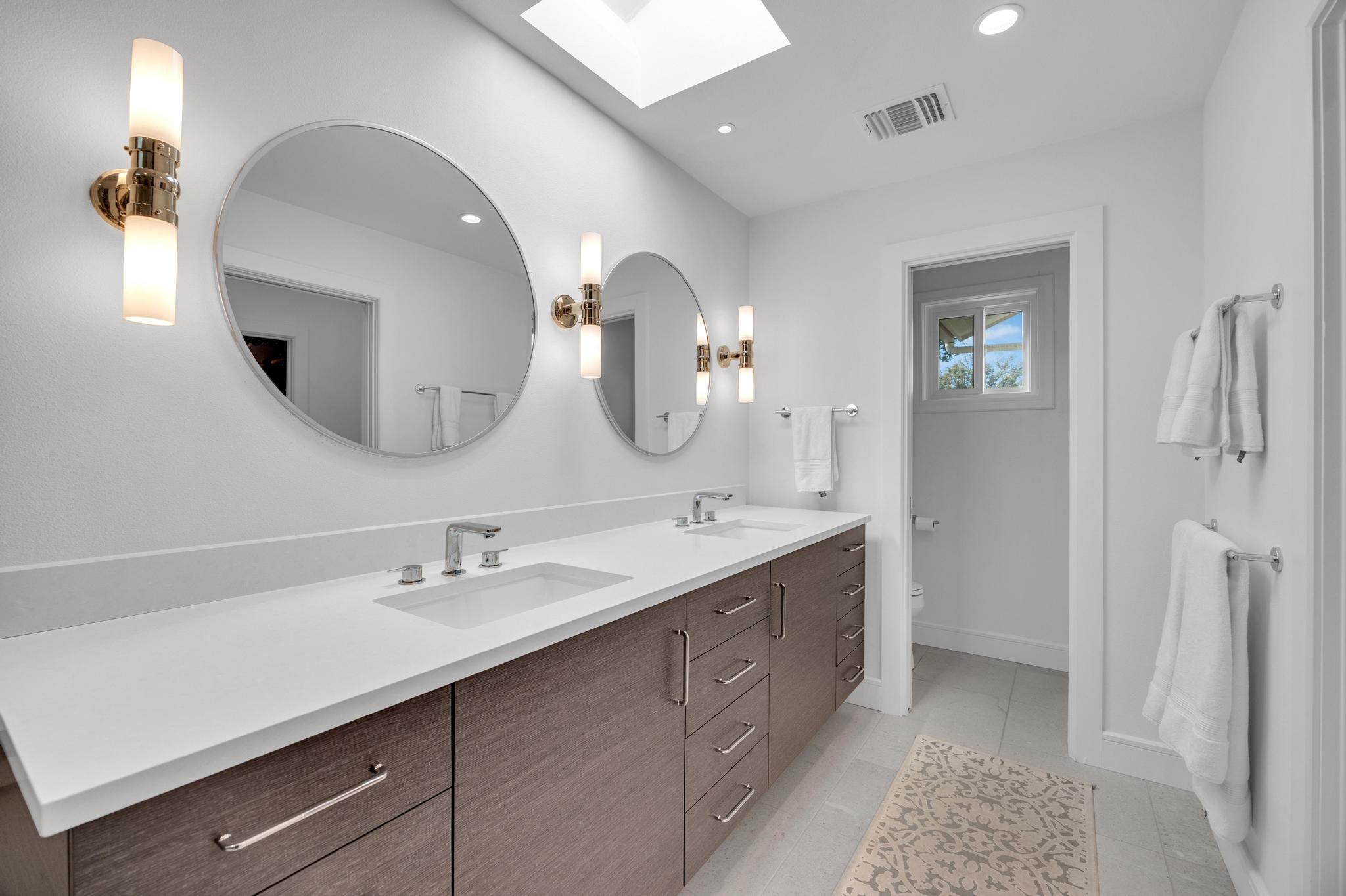 24710 Fossil Trail Spicewood, TX 78669 - Photo 16 of 40 a en suite bathroom with a double vanity sink and a mirror