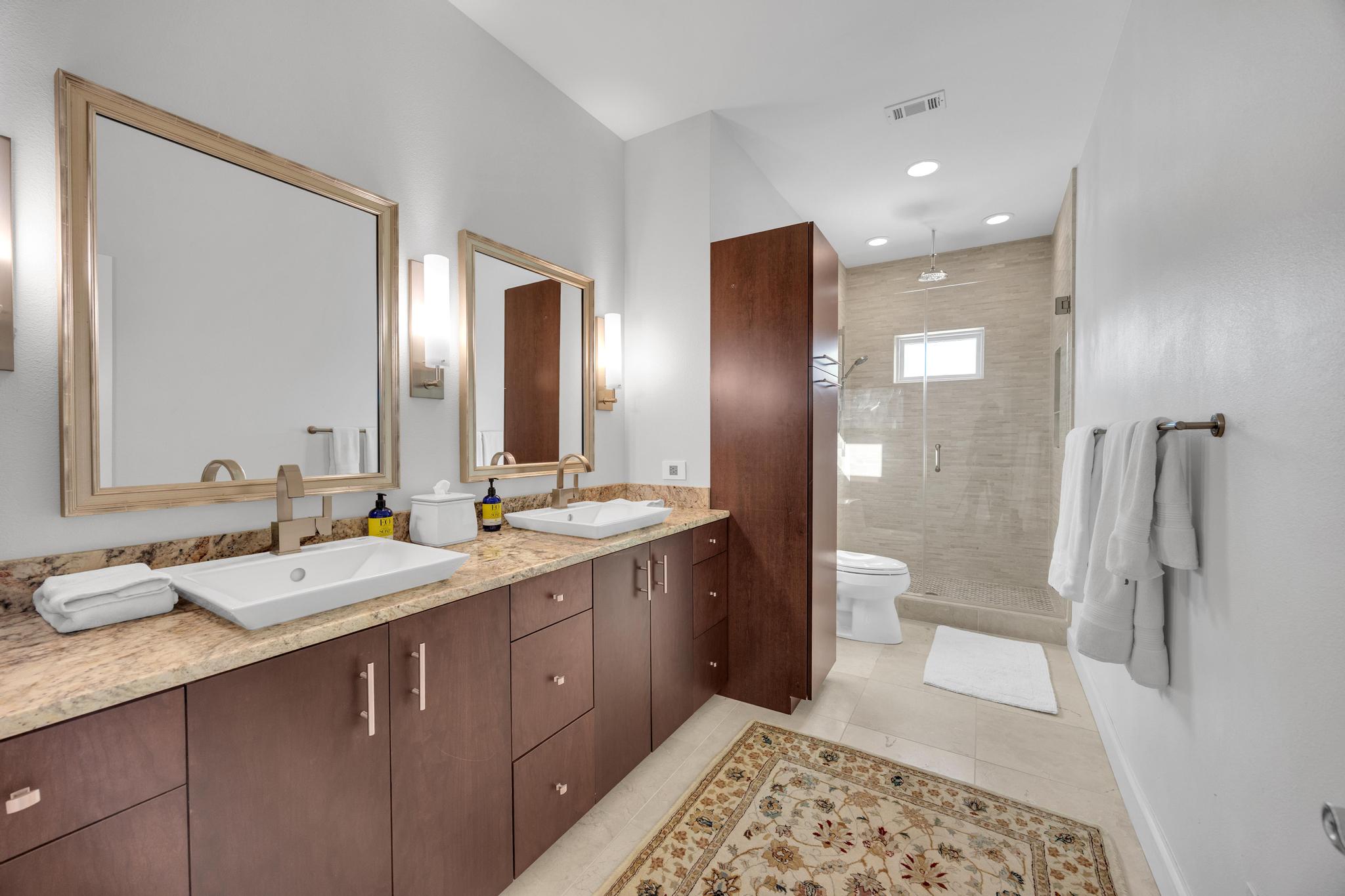 24710 Fossil Trail Spicewood, TX 78669 - Photo 22 of 40 a spacious bathroom with a double vanity sink toilet and shower