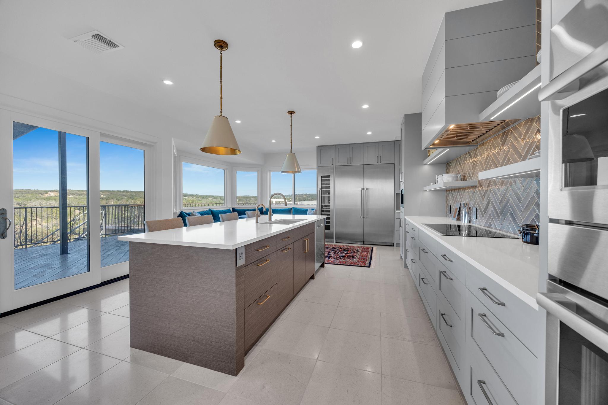 24710 Fossil Trail Spicewood, TX 78669 - Photo 10 of 40 a large kitchen with stainless steel appliances kitchen island granite countertop a sink a counter space and a view of living room