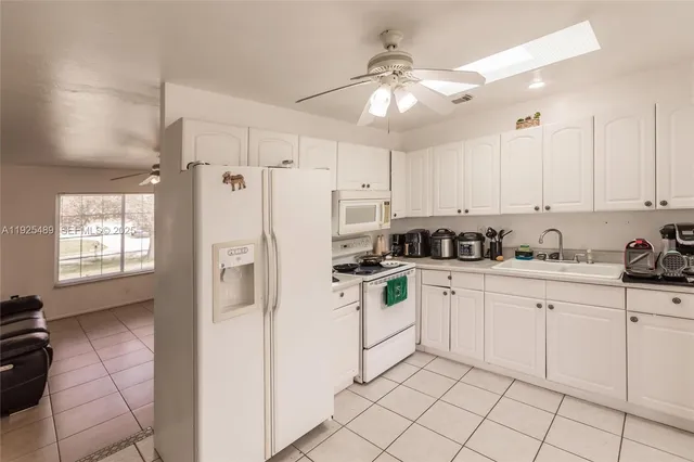a kitchen with white cabinets a sink dishwasher and white appliances