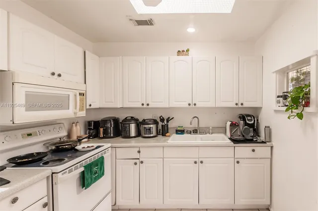 a kitchen with white cabinets and appliances