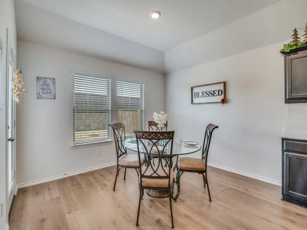 a kitchen with stainless steel appliances kitchen island granite countertop a table chairs and a refrigerator