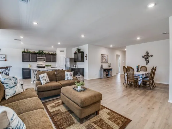 a kitchen with stainless steel appliances a stove top oven a sink dishwasher a refrigerator and a dining table with wooden floor