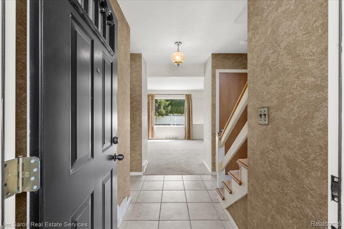 1010 Nottingham Road Grosse Pointe, MI 48230 - Photo 5 of 30 Entryway featuring a black paneled front door, ceramic tile flooring, textured wall finishes, and a traditional pendant light fixture