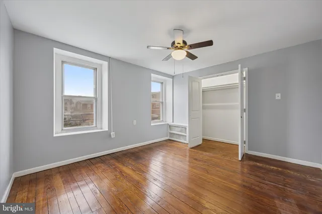 a view of an empty room with a window and wooden floor