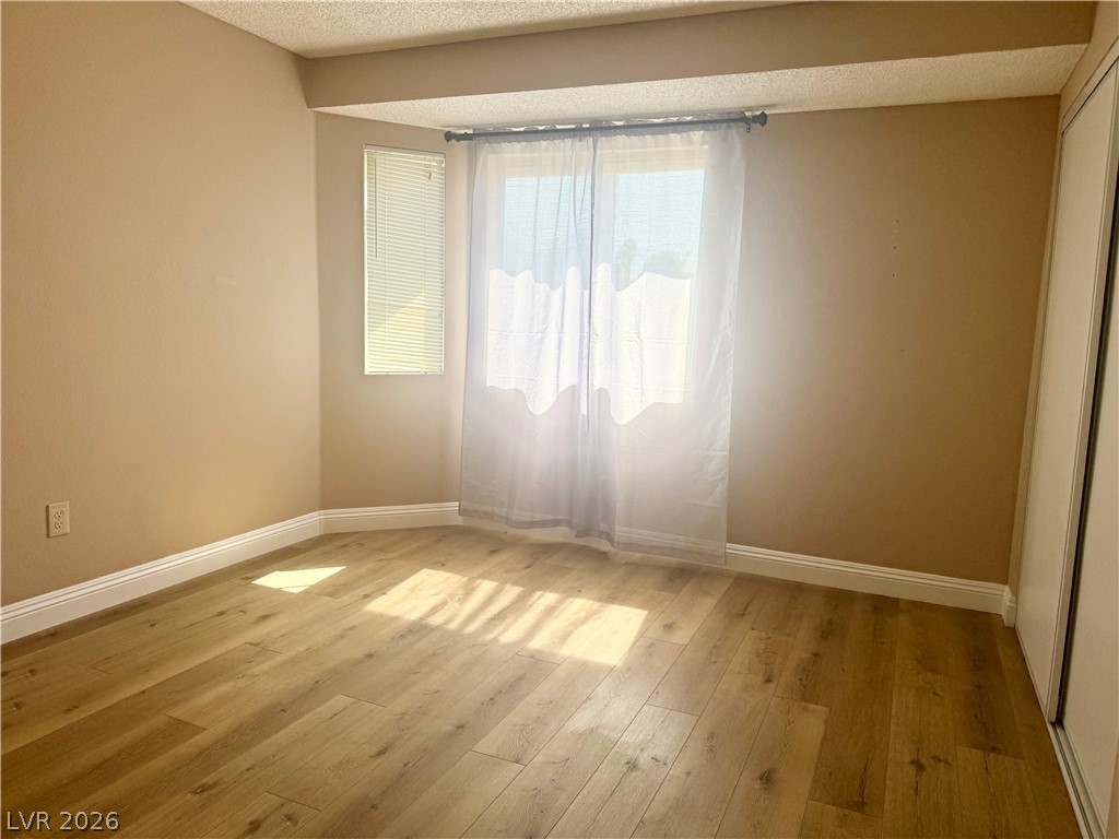 135 Primero Way Henderson, NV 89074 - Photo 11 of 15 Golden light bathes this spacious room, revealing durable wood flooring and ample closet storage.