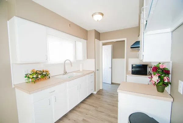 a white kitchen with a sink and a large window