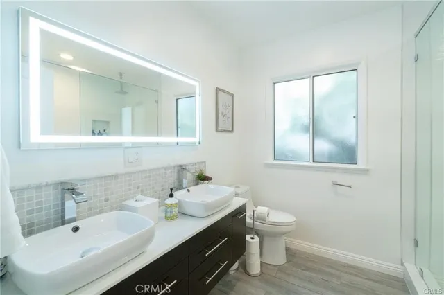 a bathroom with a double vanity sink toilet and mirror