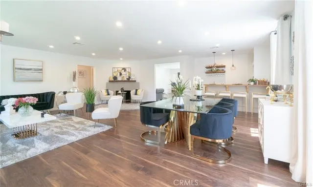 a living room with furniture a wooden floor and kitchen view