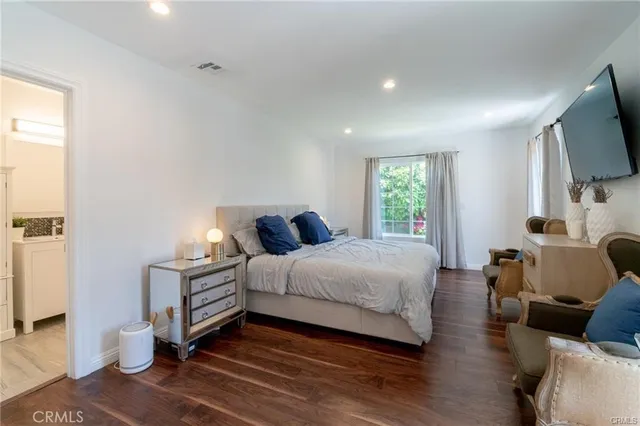 a spacious bedroom with a bed a couch and a flat screen tv