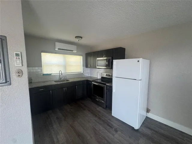 a kitchen with a refrigerator a sink dishwasher with a stove and wooden floor