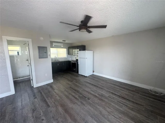 an empty room with wooden floor cabinet and windows