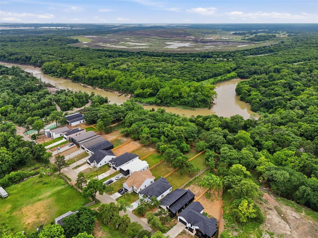 1111 Riverwood Road Dallas, TX 75217 - Photo 37 of 40 Aerial perspective showcasing a residential development bordered by a winding river and extensive natural tree coverage