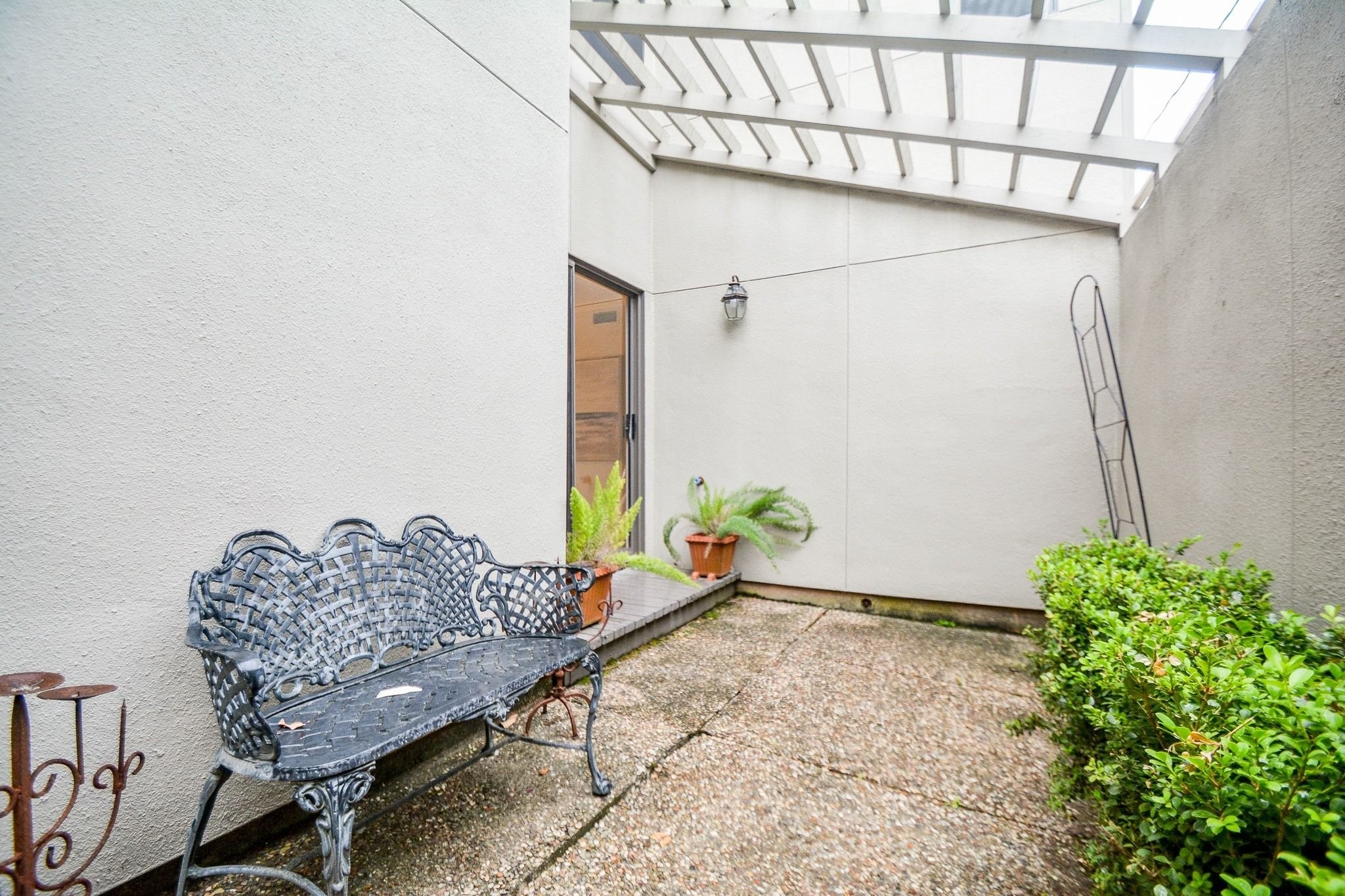 820 Harold Street Houston, TX 77006 - Photo 30 of 33 A tucked-away courtyard off the living room offers a quiet outdoor escape with a pergola overhead, wrought iron seating, and lush potted greenery.